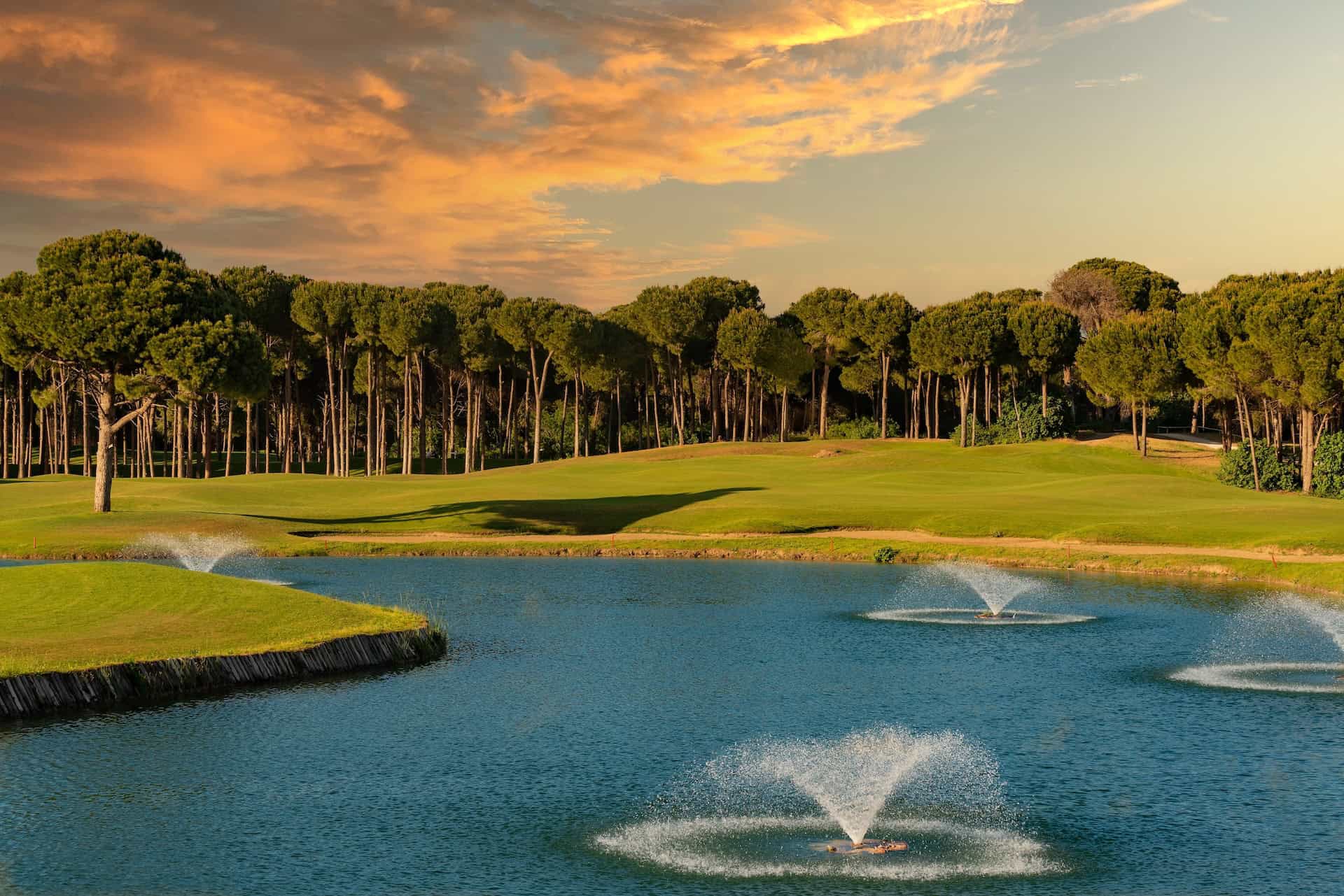 Aerial of a golf course with a large water hazard featuring numerous fountains