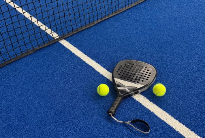 A padel racket and balls on a court
