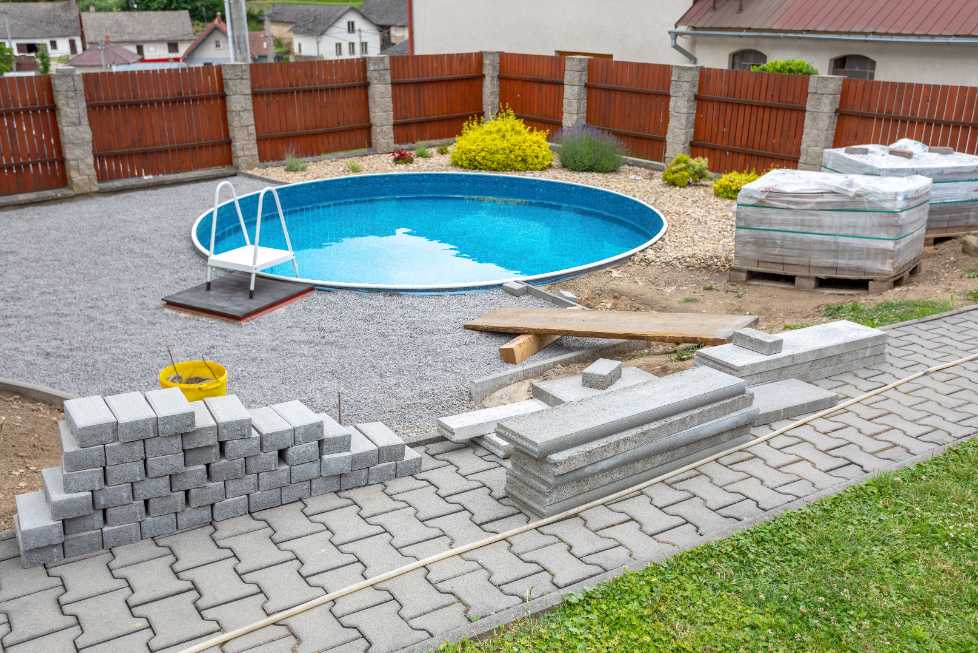 round in-ground swimming pool with unfinished landscaping in the final stages of completion