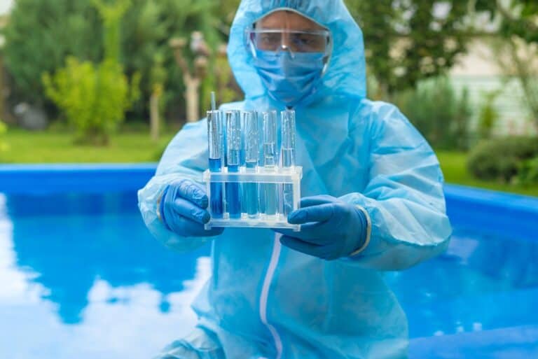 a person in proper protective gear analyzes a pool water reading