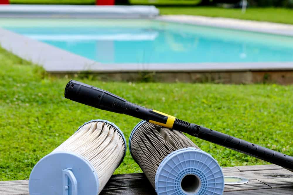 Pool filter being cleaned with a hose as part of regular pool maintenance