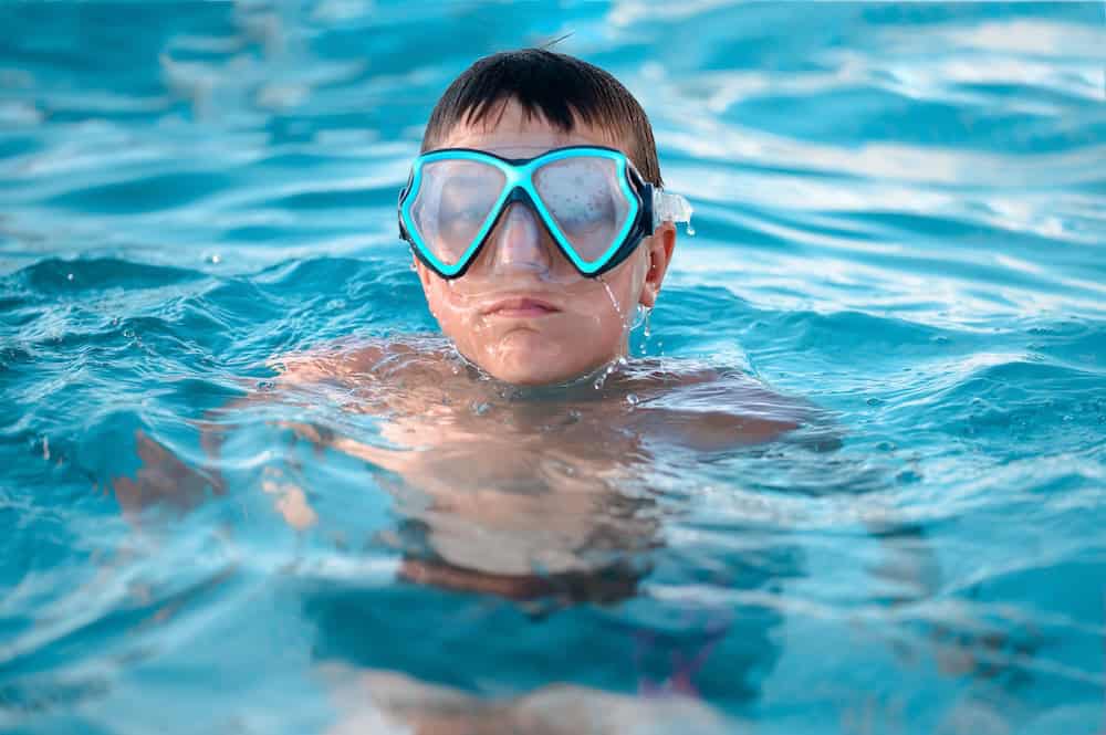 A boy wearing swimming goggles in a pool