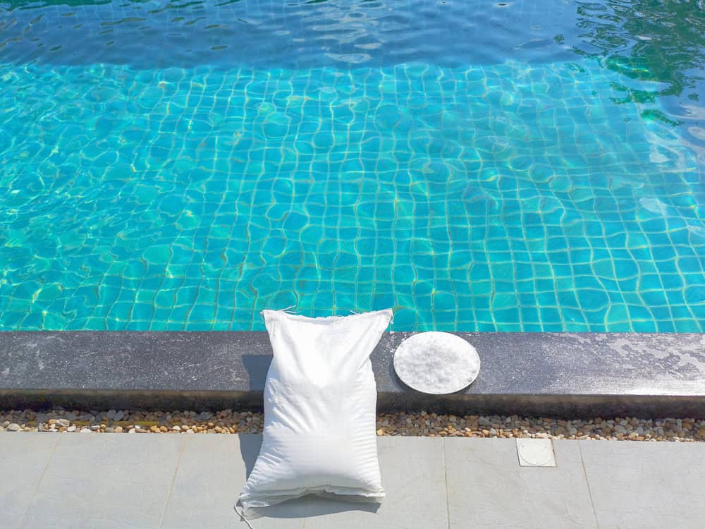 Pool technician testing salt water pool chemistry and salt level near swimming pool