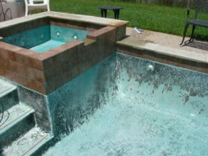 An emptied commercial swimming pool with dark organic pool stains spreading across its floor.