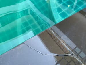 A damaged pool edge with visible cracks indicating the need for pool leak repair