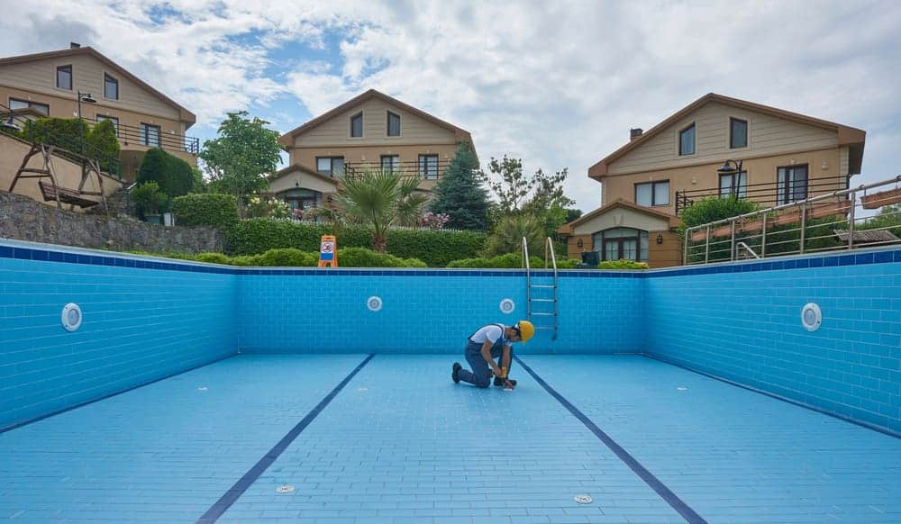 A technician repairing pool equipment to resolve swimming pool leaks at a residential property